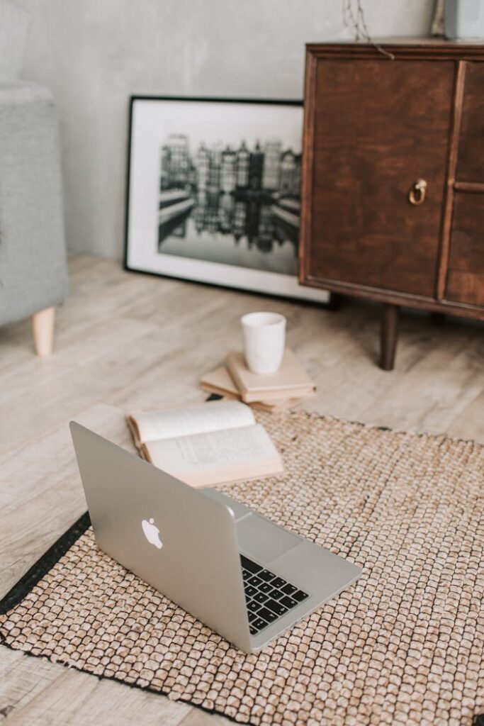 A serene workspace with a laptop, open book, and coffee cup on a textured rug, ideal for remote work.